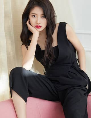 in black jumpsuit sitting on a pink chair